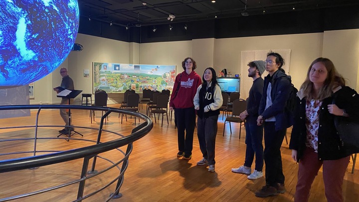 Students listening to a presentation with a digital projection globe