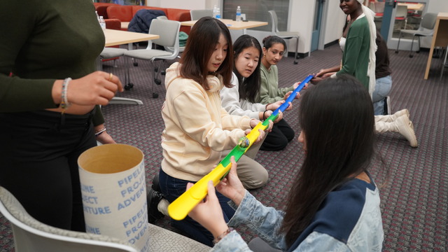 Students working together to complete a challenge to roll a ball down a track